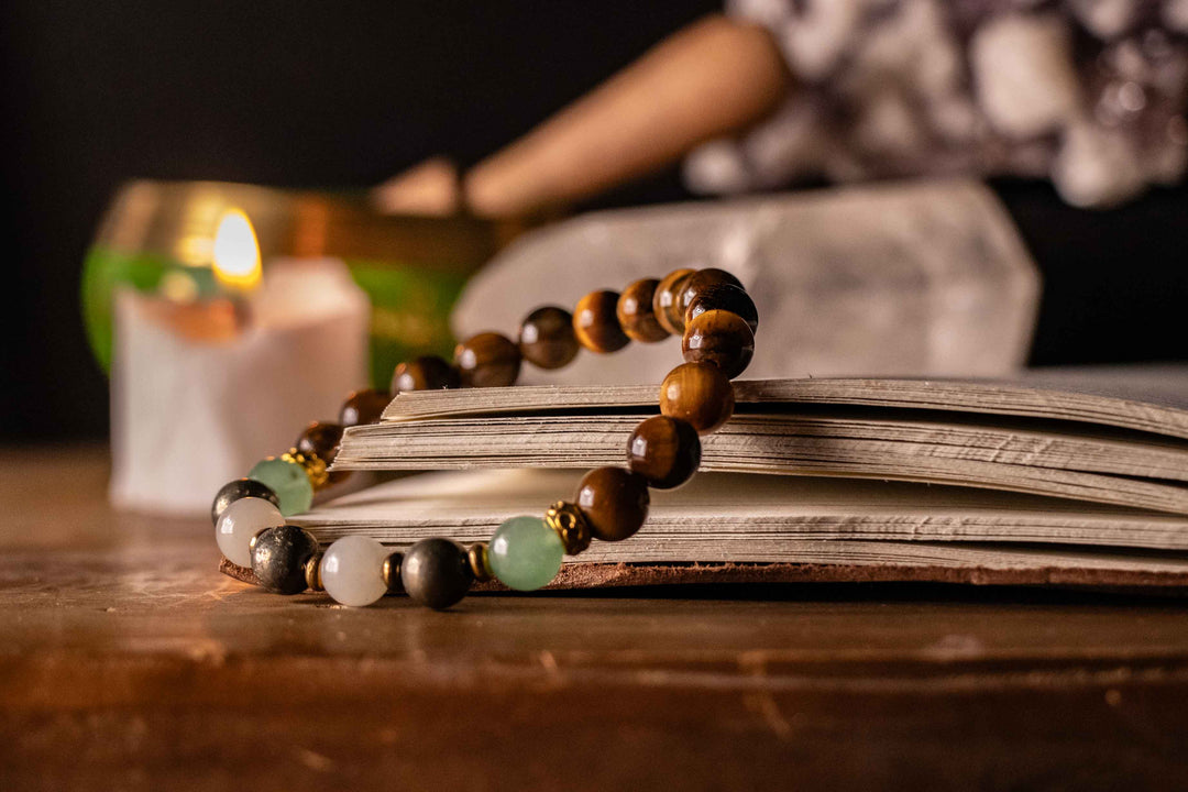 Crystal bracelet resting on an open journal beside a lit candle and crystals, creating a calm money manifestation and abundance ritual setting.