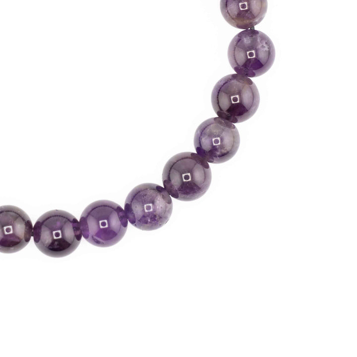 Close-up detail of smooth, polished round Amethyst gemstone beads showcasing rich violet hues and natural clarity variations