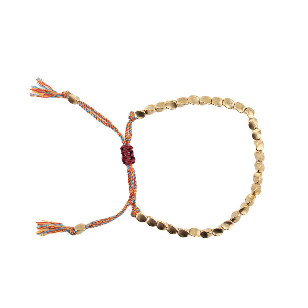 An adjustable bracelet featuring organic-shaped gold copper beads on a multi-colored (blue, orange, and red) braided cord with a sliding knot closure and tassel ends.