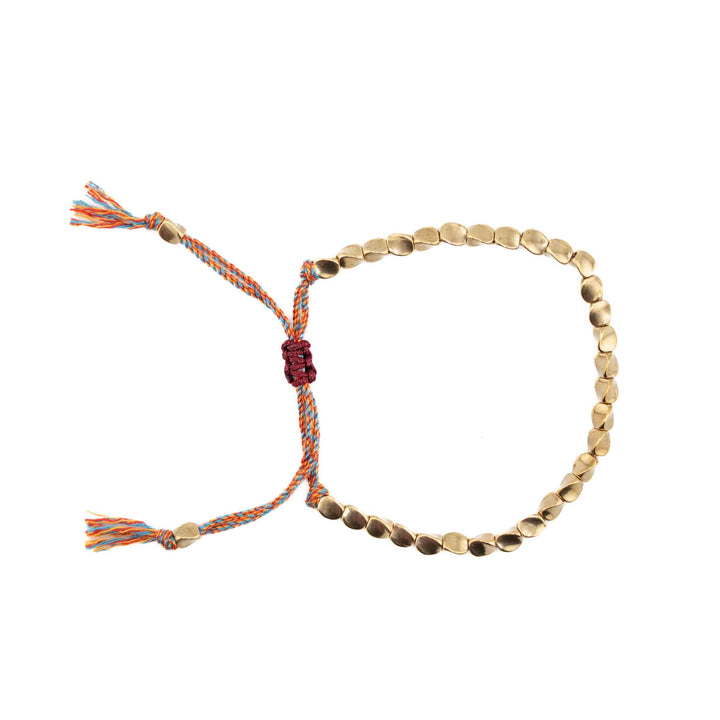 An adjustable bracelet featuring organic-shaped gold copper beads on a multi-colored (blue, orange, and red) braided cord with a sliding knot closure and tassel ends.