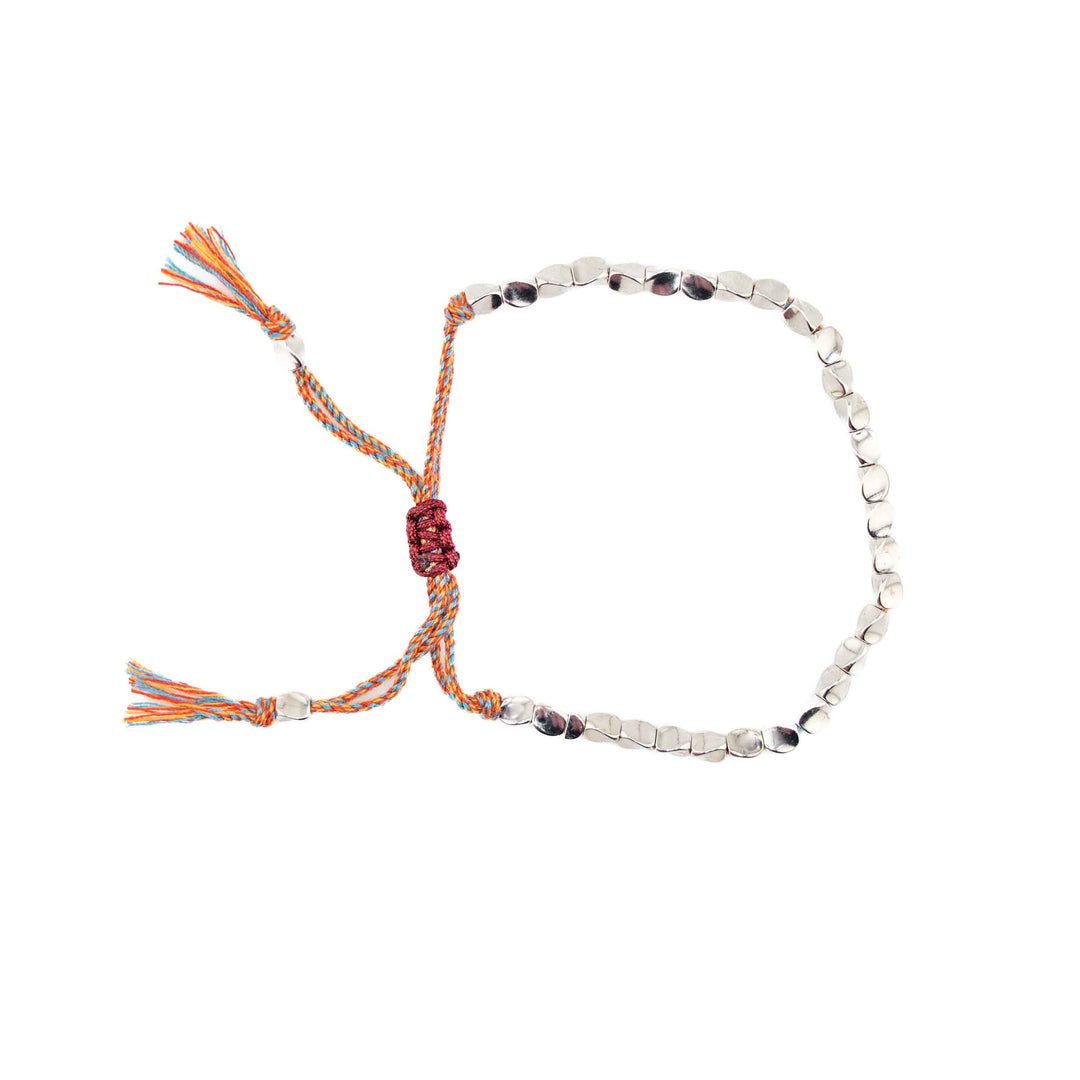 An adjustable bracelet featuring organic-shaped silver-colored copper beads on a multi-colored braided cord with a sliding knot closure and tassel ends.