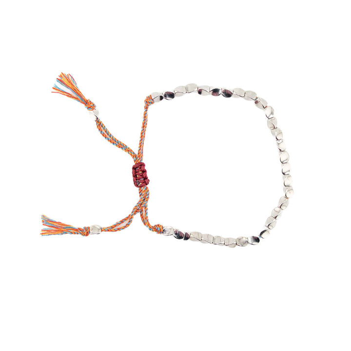An adjustable bracelet featuring organic-shaped silver-colored copper beads on a multi-colored braided cord with a sliding knot closure and tassel ends.