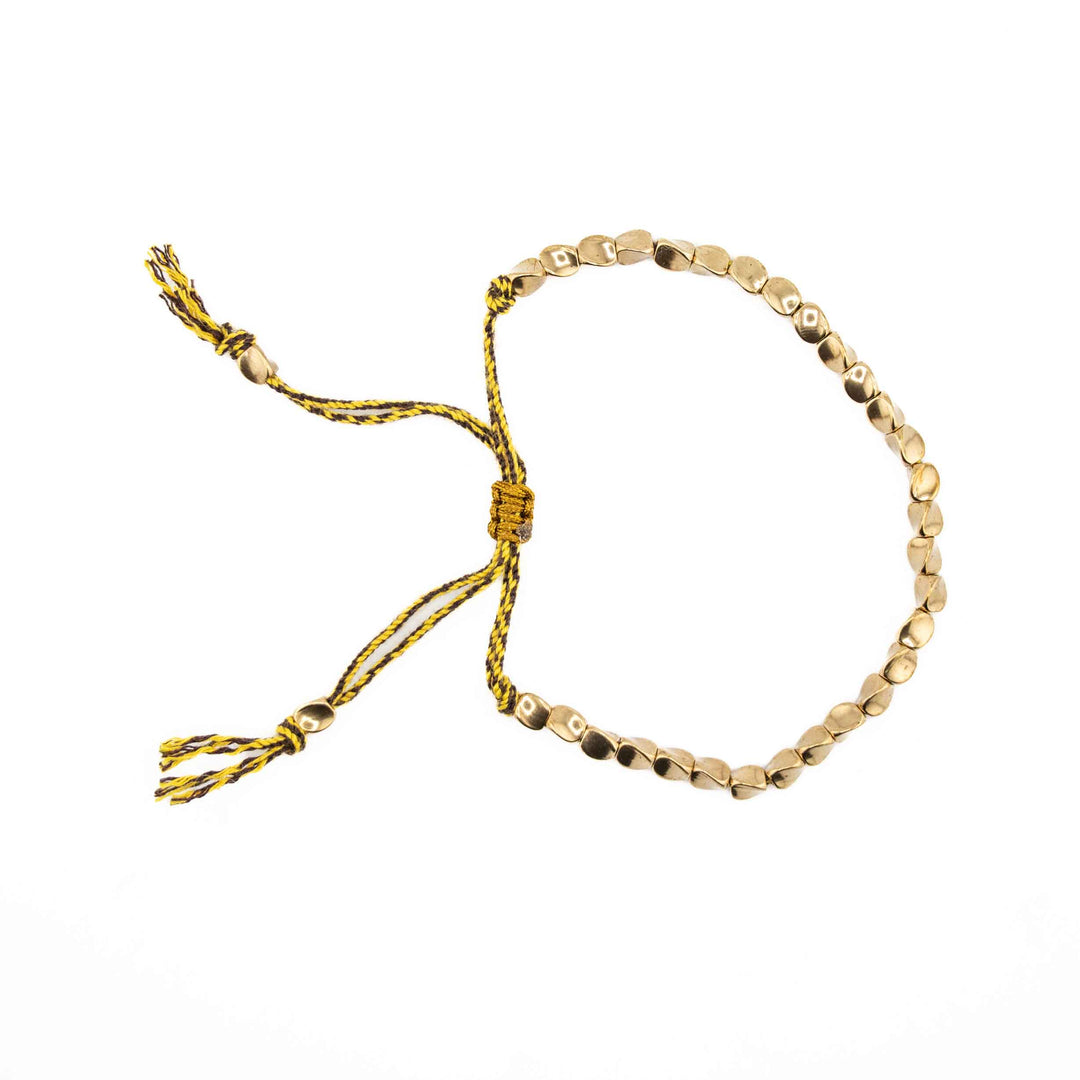 An adjustable bracelet featuring organic-shaped gold copper beads on a yellow braided cord with a sliding knot closure and tassel ends.