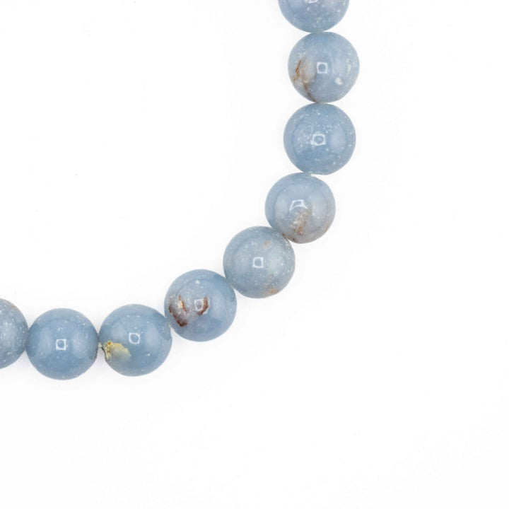 Close-up detail of polished round Angelite beads showing light blue color tones and natural mineral flecks