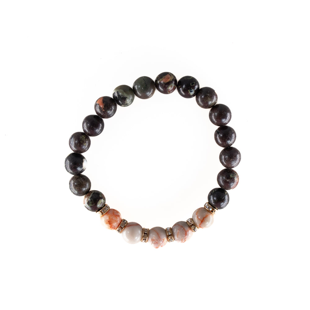 A circular beaded bracelet featuring glossy dark and lighter marbled orange and white gemstone beads accented with small gold-toned spacers embedded with clear rhinestones on a white background