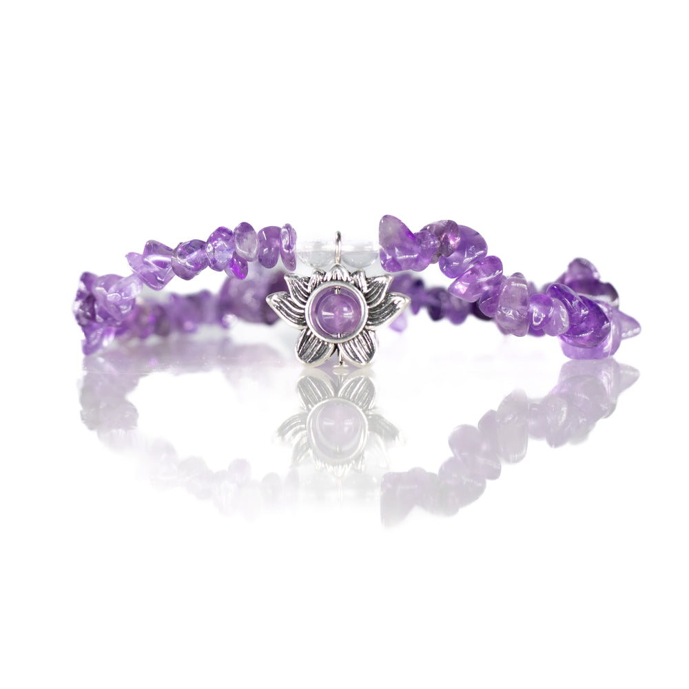Amethyst chip bead bracelet featuring a silver lotus charm with a purple center bead and clear spacer beads on a reflective white surface