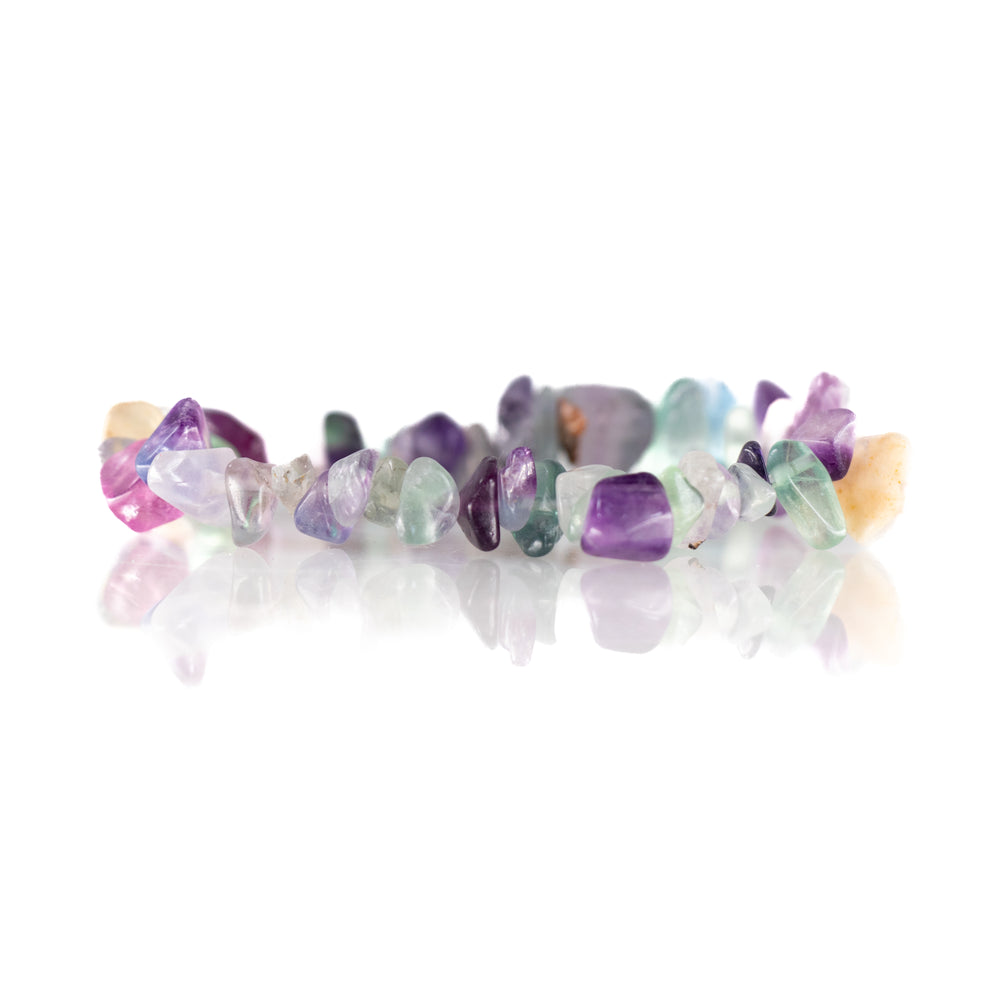 Studio shot of a vibrant gemstone chip bracelet featuring polished irregular fluorite in shades of purple, green, blue, yellow, and pink on a reflective white surface
