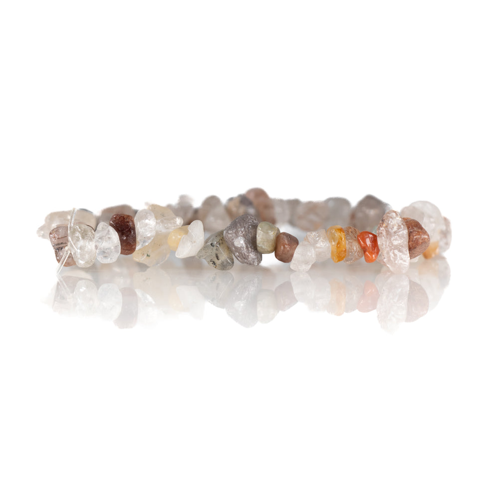 A natural gemstone chip bracelet featuring varied clear and opaque stones in irregular shapes and colors of white, gray, orange, and brown on a reflective white surface
