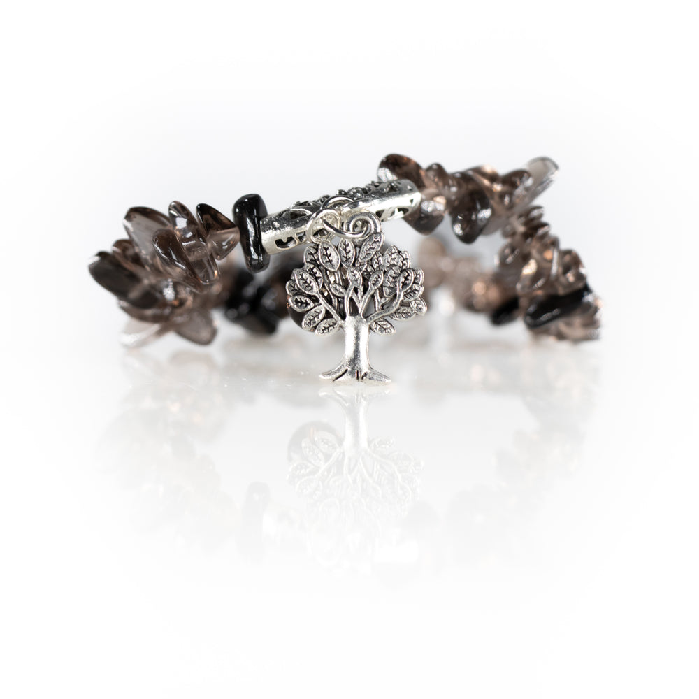 A polished beaded bracelet with dark brown or smoky quartz stones, a prominent silver tree of life charm, and an ornate silver toggle clasp reflecting on a white background