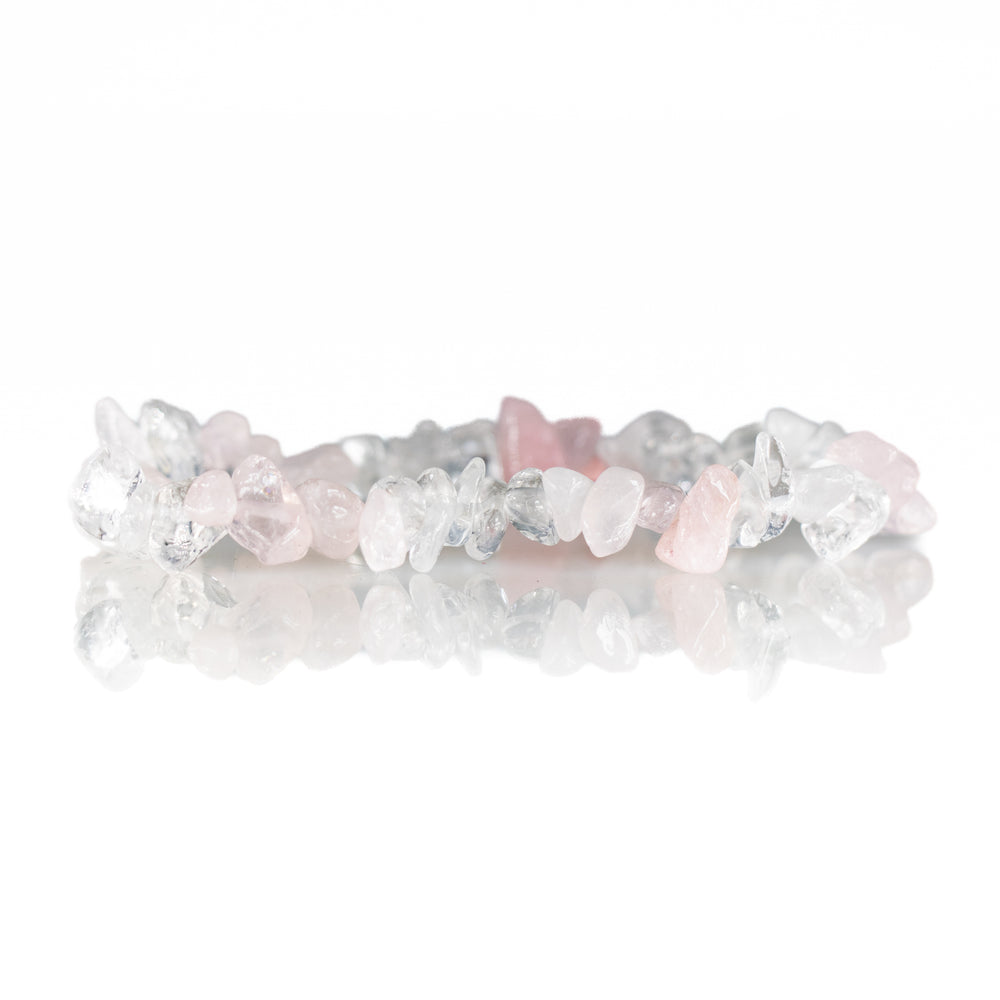 Photograph of a crystal chip bracelet featuring pale pink rose quartz and sparkling clear quartz stones on a reflective white surface creating a soft reflection