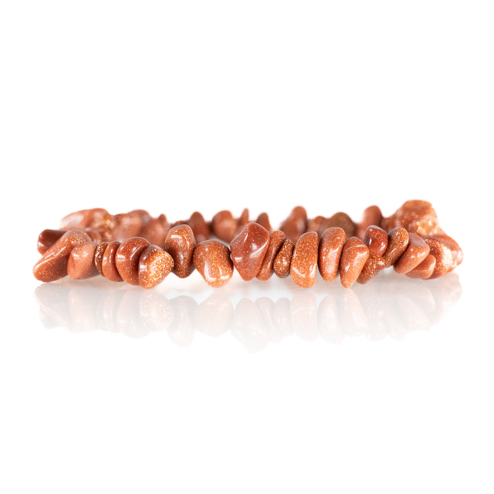 A reddish-brown goldstone chip bracelet featuring sparkling copper flecks in its polished irregularly shaped beads reflected on a white surface