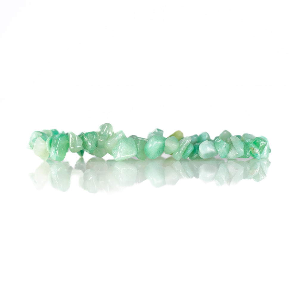 Photograph of a green gemstone chip bracelet in a studio setting featuring irregular tumbled aventurine stones vibrant light green hues and a subtle reflection on a white surface
