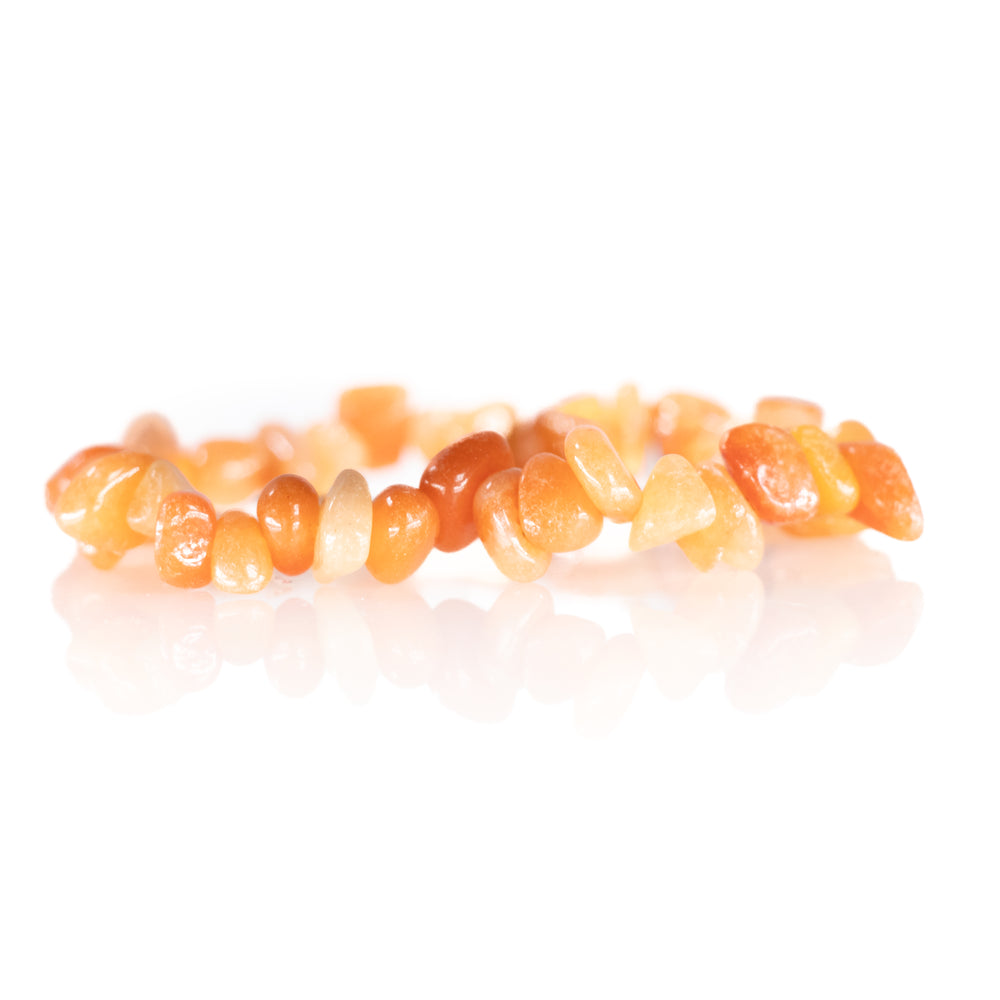 Natural gemstone bracelet of vibrant tumbled carnelian beads ranging from light peach to deep orange with a clear reflection on a crisp white studio background