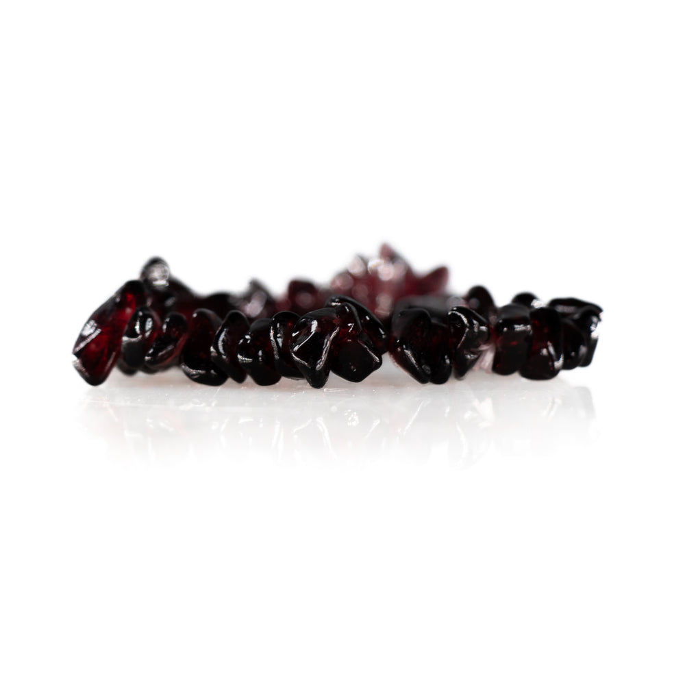 Dark red chip cut gemstone bracelet with a glossy finish reflecting on a white surface