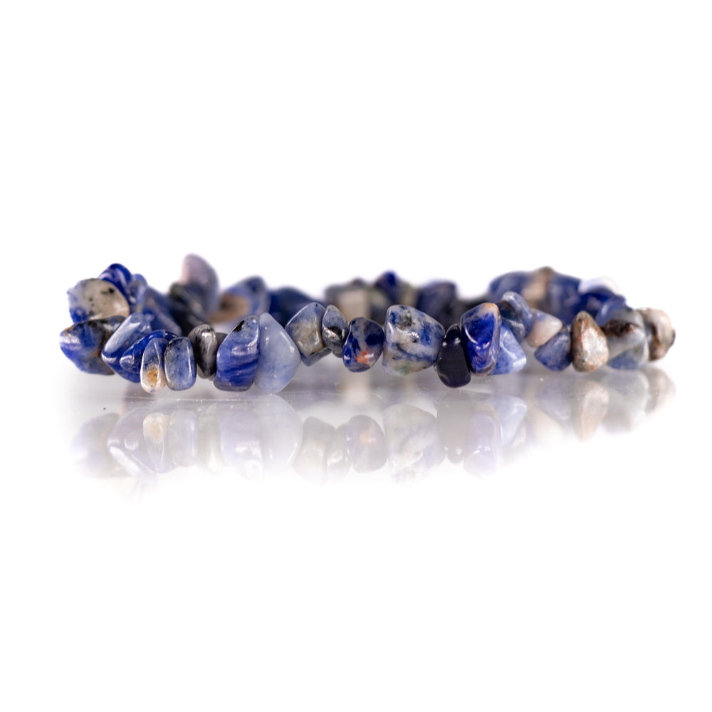 Jewelry product photo of a sodalite chip bracelet featuring irregular deep blue and white tumbled stones reflecting on a bright white studio surface