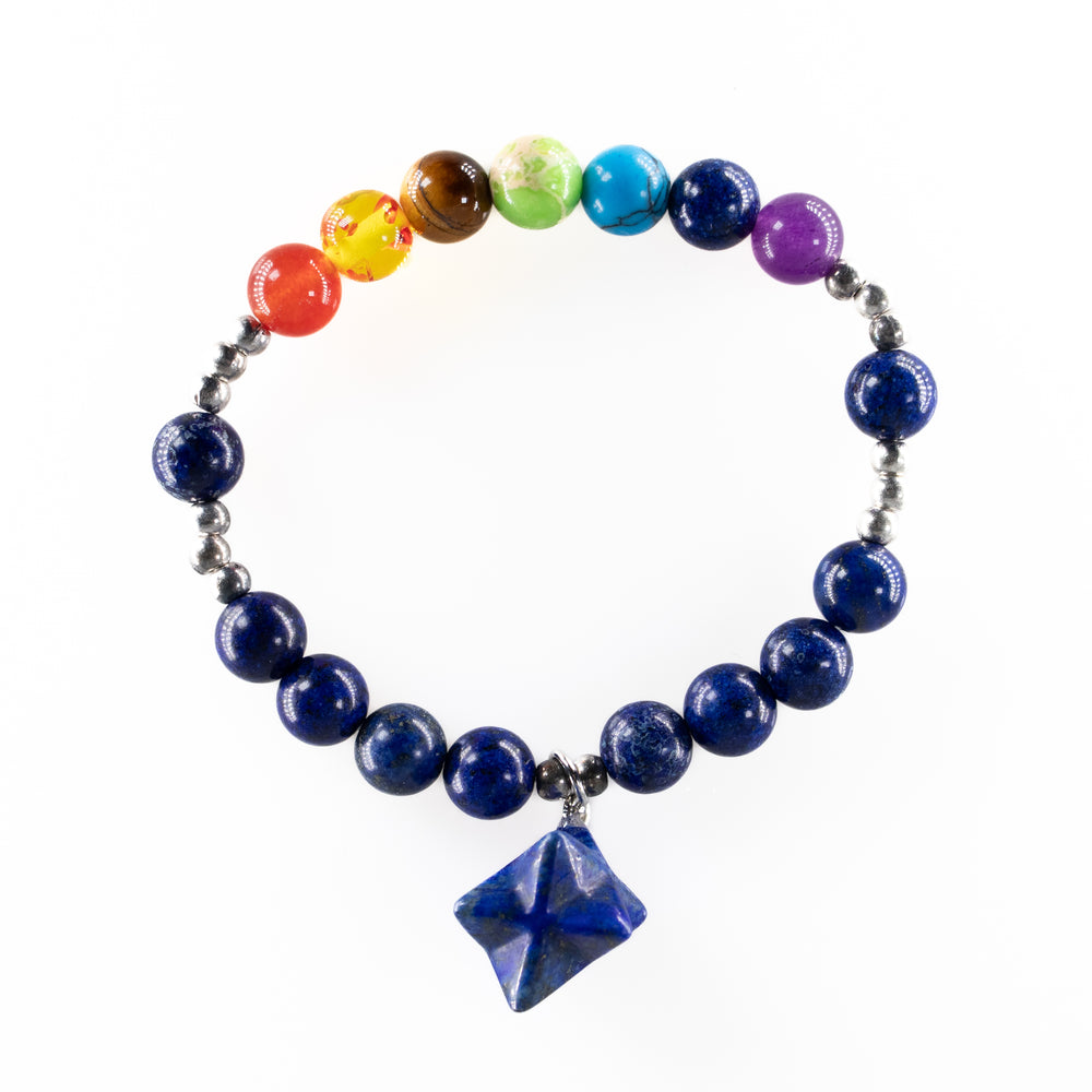 Beaded bracelet featuring a vibrant arc of rainbow chakra-colored beads transitioning into dark blue lapis lazuli beads with silver spacers and a unique four-pointed lapis lazuli star charm against a pristine white background