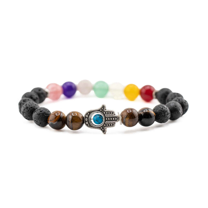 Side view resting shot showing silver Hamsa hand charm centered between tiger eye beads, lava stones, and pastel chakra beads on a stretch bracelet