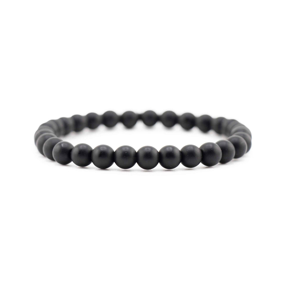 Side view resting shot of a Frosted Black Onyx gemstone beaded stretch bracelet lying flat on a white background