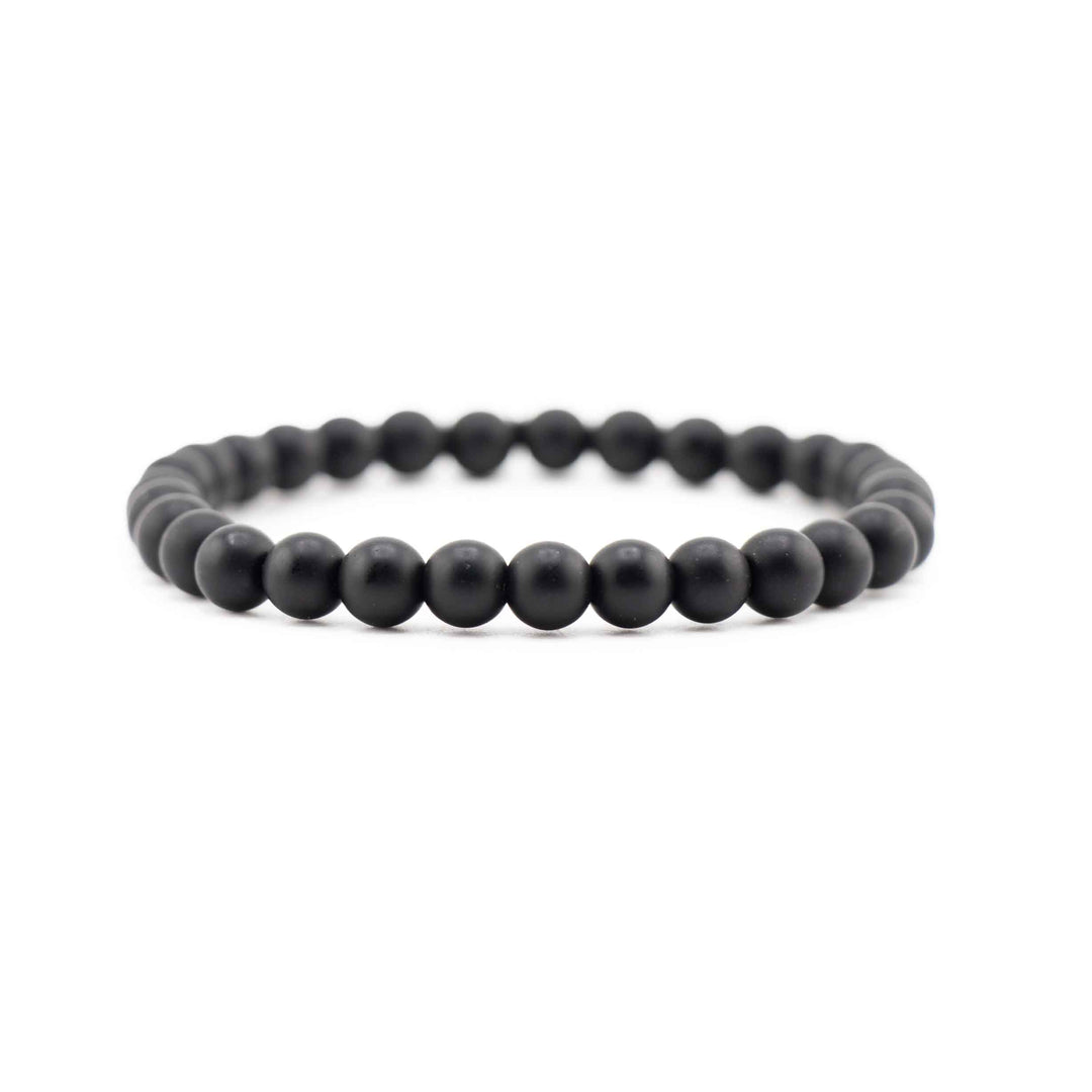 Side view resting shot of a Frosted Black Onyx gemstone beaded stretch bracelet lying flat on a white background