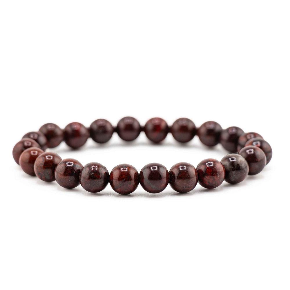 Side view resting shot of a natural Bloodstone gemstone beaded stretch bracelet lying flat on a white background