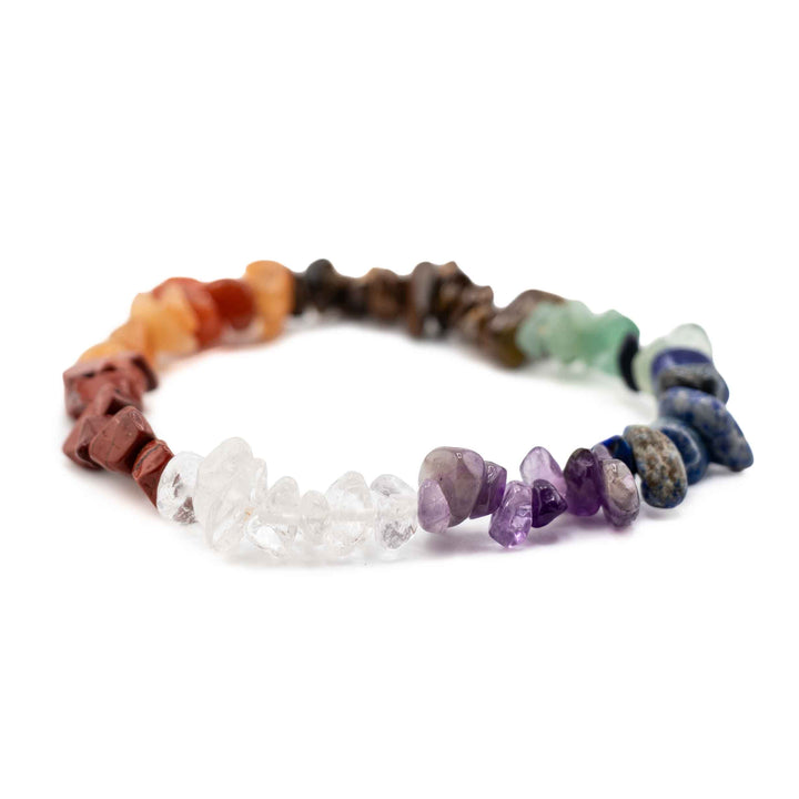 Side view resting shot displaying clear quartz and purple amethyst tumbled gemstone chips on a colorful chakra stretch bracelet