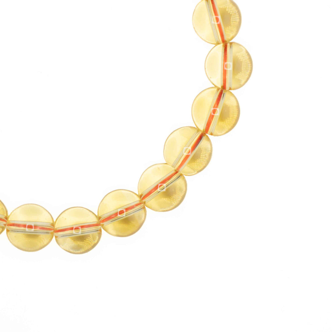 Close-up detail of smooth, round Citrine beads showing sunny light yellow clarity and threaded elastic cord