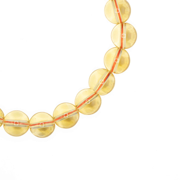 Close-up detail of smooth, round Citrine beads showing sunny light yellow clarity and threaded elastic cord