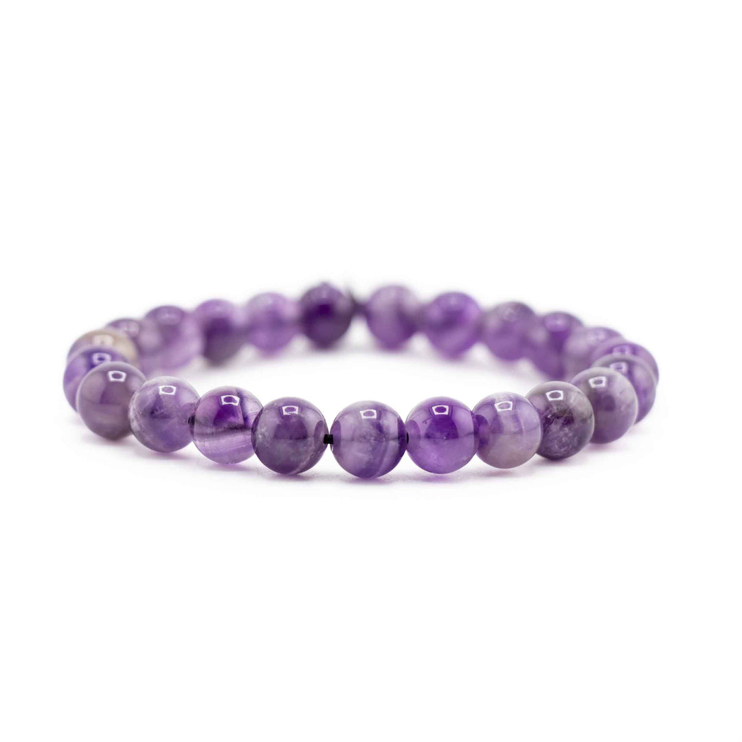 Side view resting shot of a Dream Chevron Amethyst gemstone beaded stretch bracelet lying flat on a white background