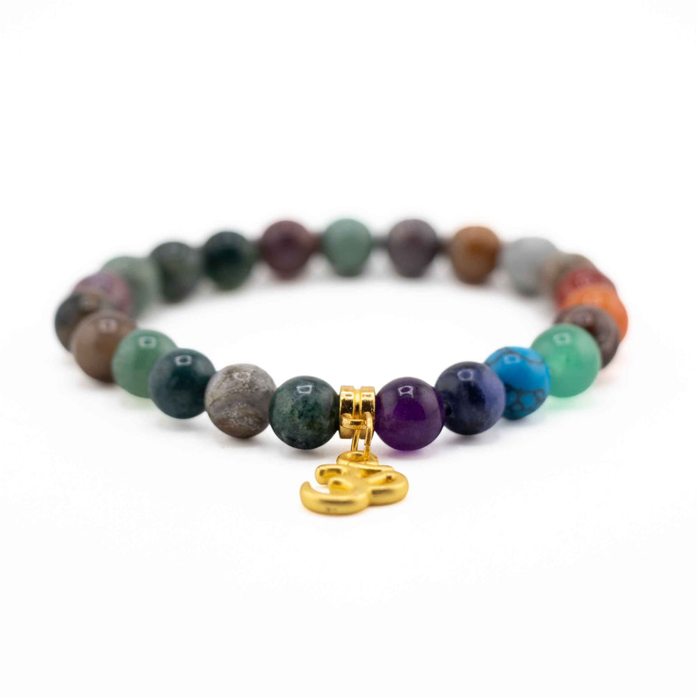 Side view resting shot displaying a gold Om symbol charm on a natural Indian Agate and colorful chakra gemstone beaded stretch bracelet
