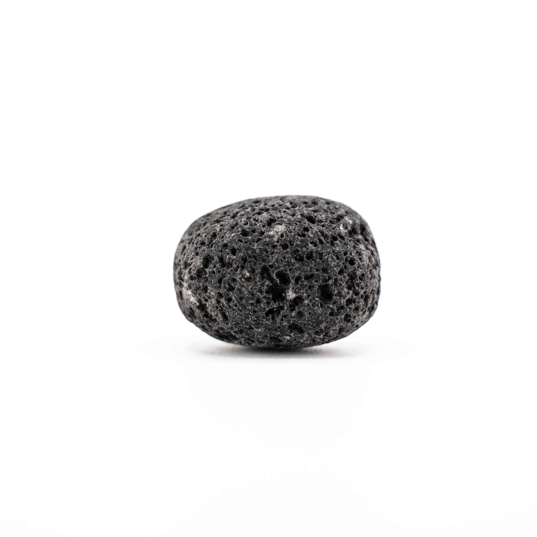 Smooth, rounded black lava stone tumbled crystal showing vesicular volcanic surface texture on a white background