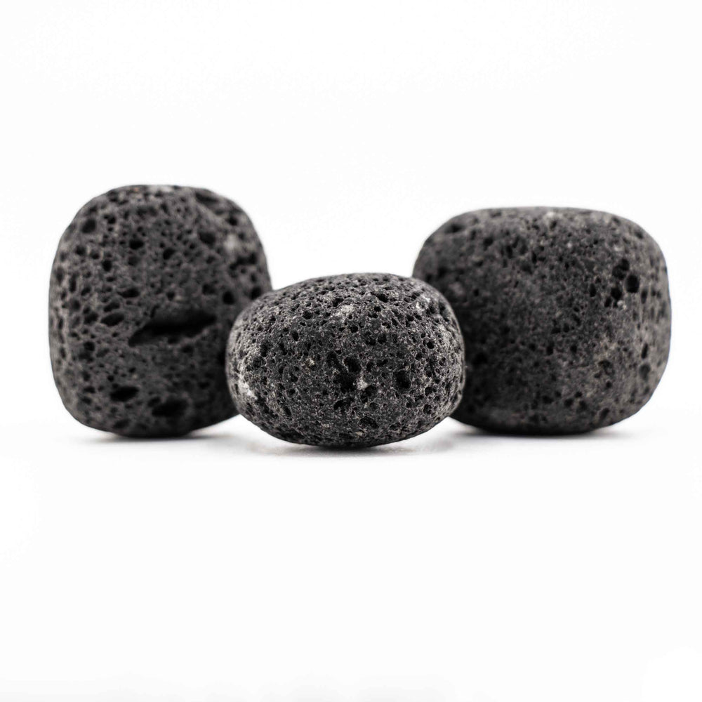 Group of three black lava stone tumbled pocket stones highlighting natural variations in shape and porous volcanic texture