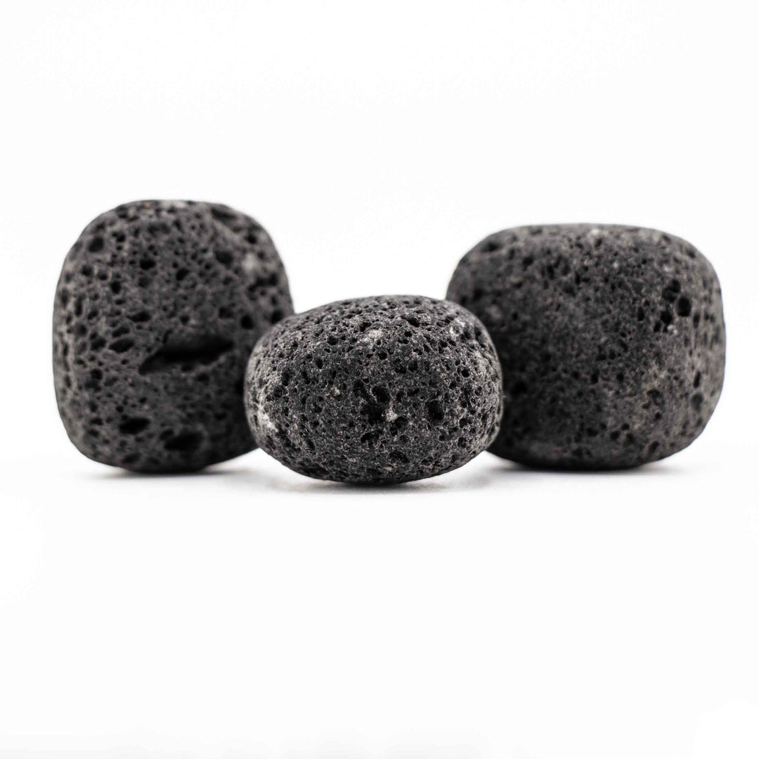 Group of three black lava stone tumbled pocket stones highlighting natural variations in shape and porous volcanic texture