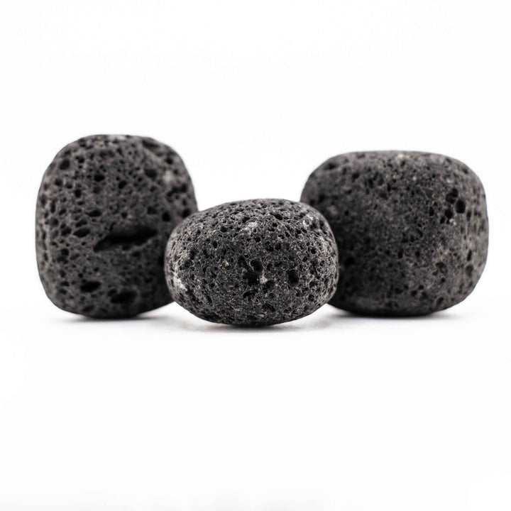 Group of three black lava stone tumbled pocket stones highlighting natural variations in shape and porous volcanic texture
