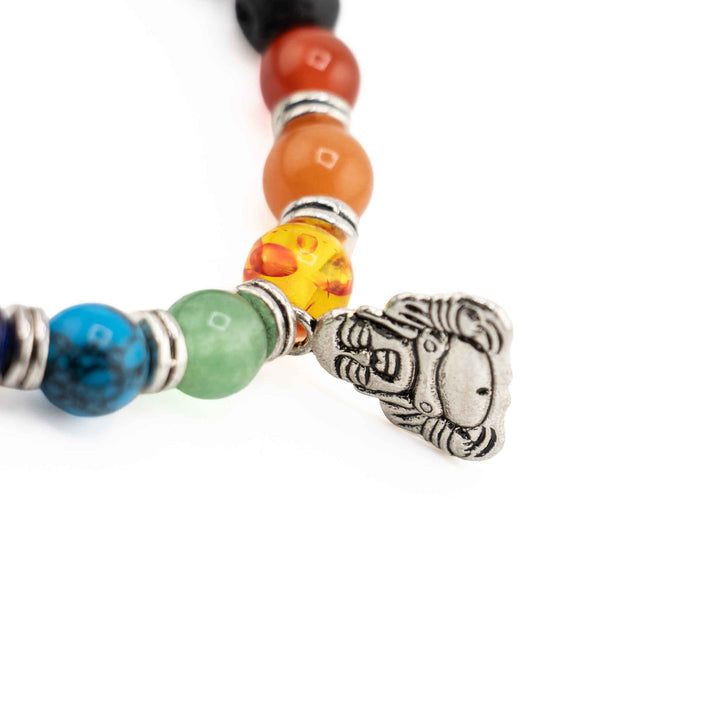 Close-up detail of silver Buddha charm attached near vibrant chakra beads with silver spacer rings on a black lava stone bracelet