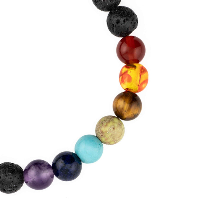 Close-up view of seven multicolored chakra gemstone beads including purple amethyst, lapis lazuli, turquoise, green, tiger eye, orange, and red beads on a black lava stone bracelet