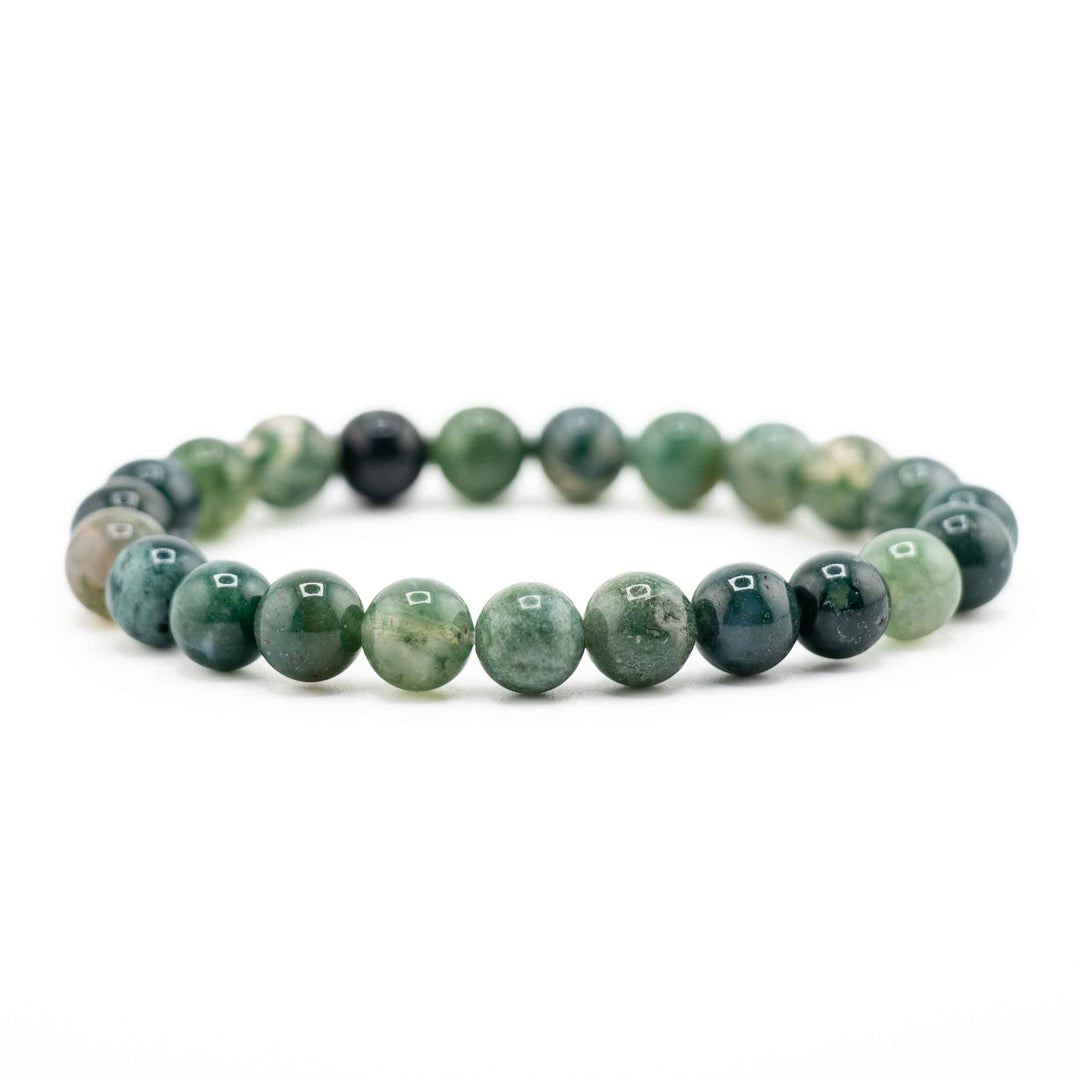 Side view resting shot of a Moss Agate gemstone beaded stretch bracelet lying flat on a white background
