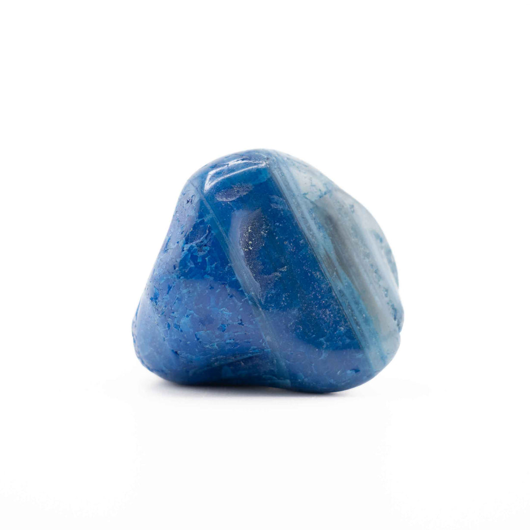 A smooth, vibrant blue-dyed agate tumbled stone centered against a plain white backdrop.