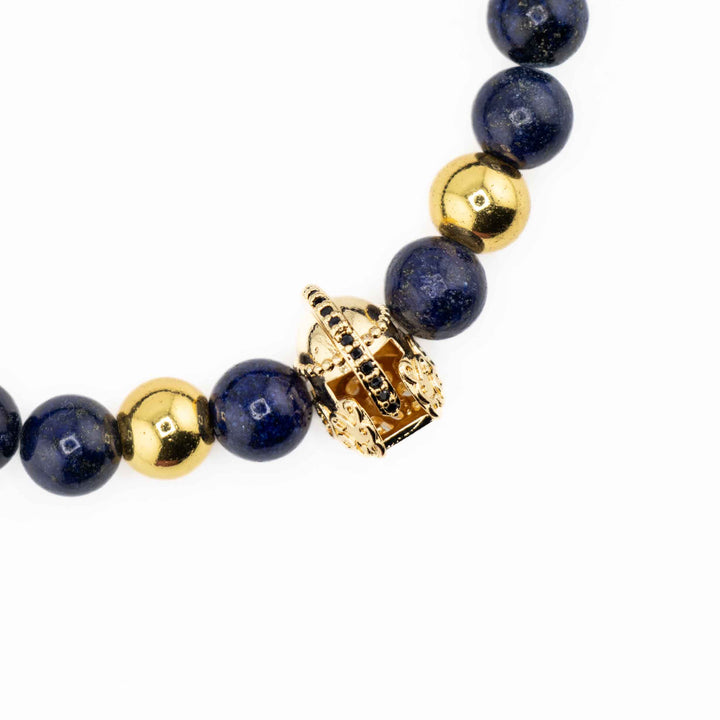 A set of three Natural Lapis Lazuli gemstone bracelets, each featuring a different gold-colored accent—an ancient helmet, a textured cylinder, and a patterned spacer bead—arranged together on a white background.