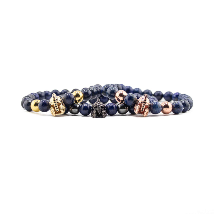 A close-up, eye-level shot of a Natural Lapis Lazuli stretch bracelet, focusing on the deep blue gemstone beads and a detailed gold-colored ancient helmet accent bead.