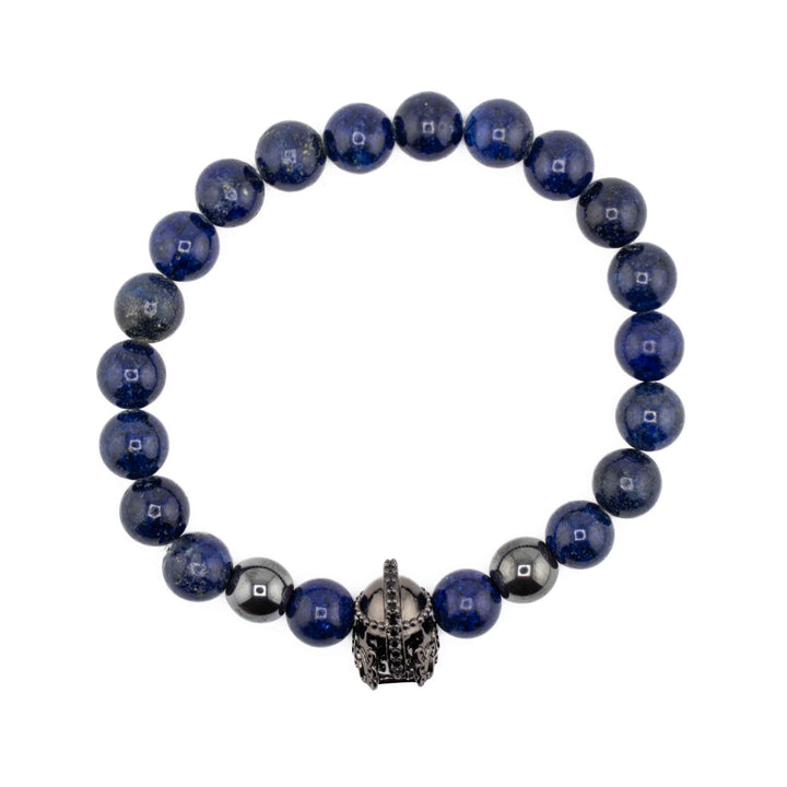 A top-down view of a Lapis Lazuli gemstone bracelet featuring round, deep blue beads and a central gold-colored ancient helmet accent bead on a white background.