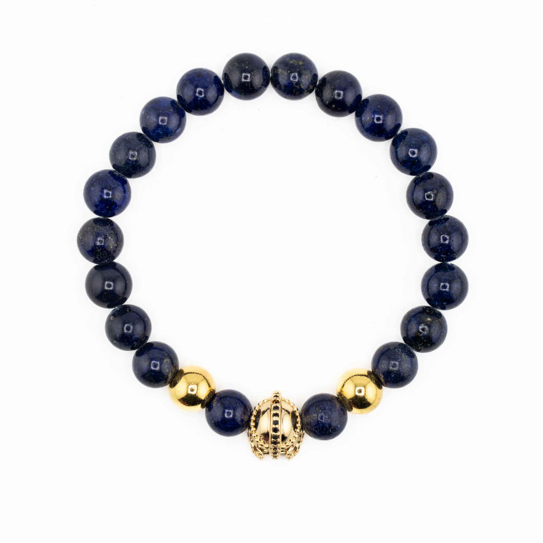 A group of three Natural Lapis Lazuli gemstone bracelets, each featuring a unique gold-colored accent—an ancient helmet, a textured barrel bead, and a simple spacer—displayed together on a white background.