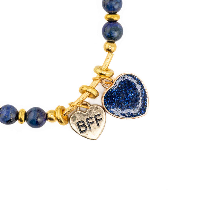 A close-up, low-angle shot of a Natural Lapis Lazuli stretch bracelet, highlighting the deep blue polished beads and a silver heart-shaped charm.