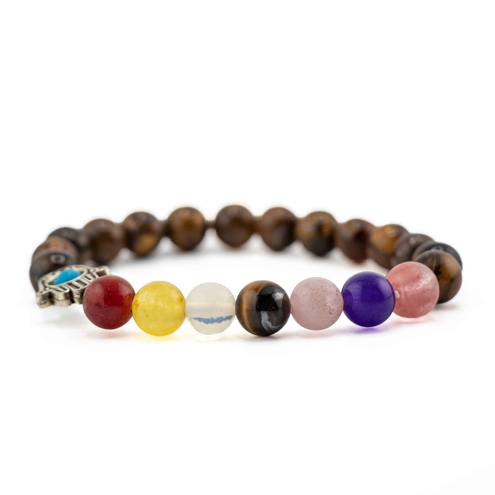 Side view resting shot showing colorful chakra gemstone beads in red, yellow, clear, purple, and pink on a brown Tiger Eye beaded bracelet