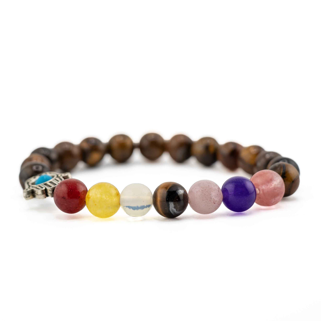 Side view resting shot showing colorful chakra gemstone beads in red, yellow, clear, purple, and pink on a brown Tiger Eye beaded bracelet