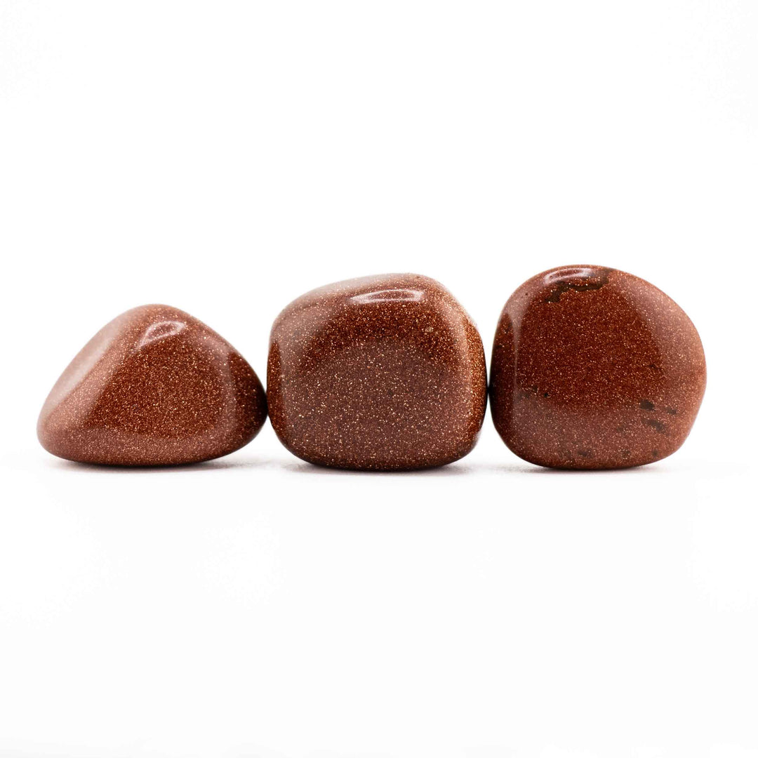 Row of three polished Red Goldstone tumbled stones displaying various natural shapes and sparkling reddish-gold finishes