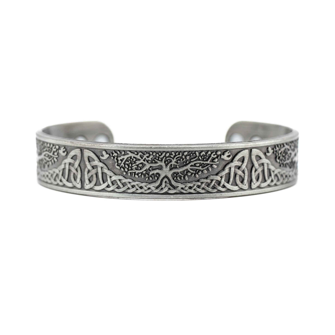 A silver-colored copper bangle bracelet featuring a central "Tree of Life" charm and small metallic beads on a white background.