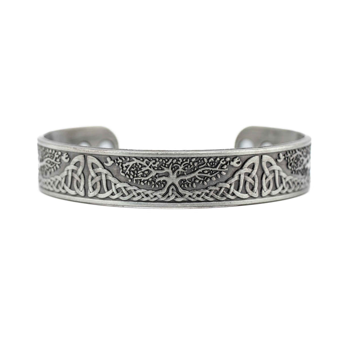 A silver-colored copper bangle bracelet featuring a central "Tree of Life" charm and small metallic beads on a white background.