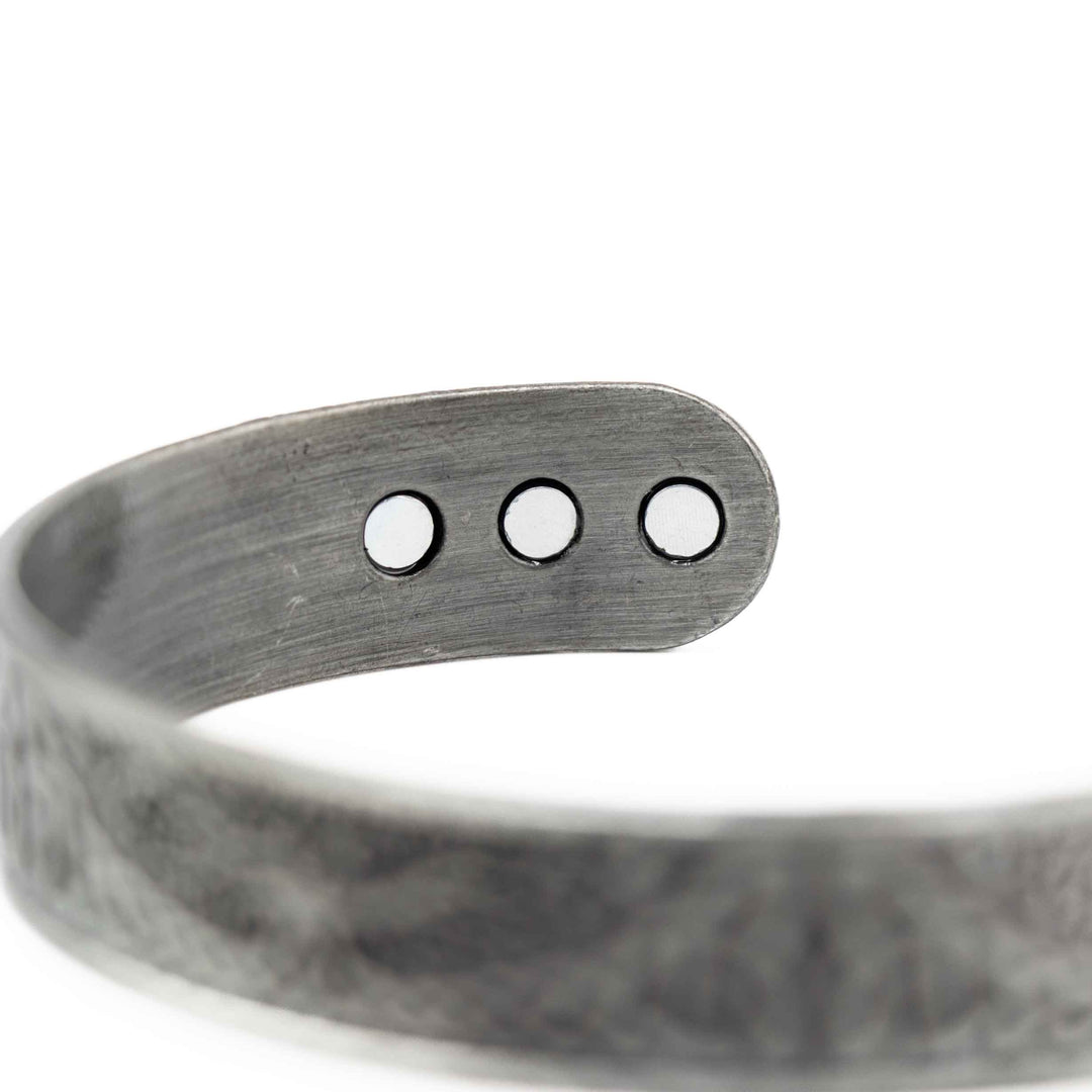 Silver bracelet with three round magnets on a white background