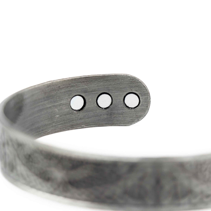 Silver bracelet with three round magnets on a white background