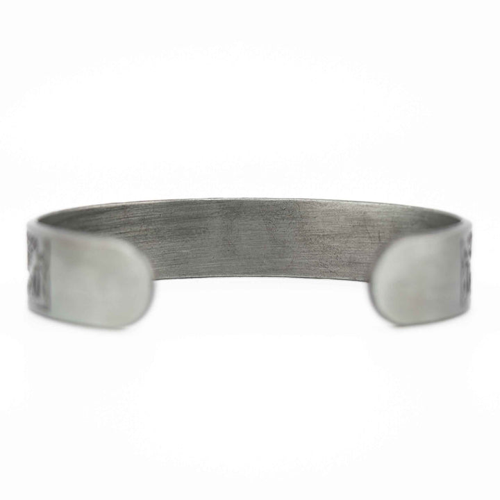A close-up, horizontal view of the silver-colored copper bangle, focusing on the intricate Tree of Life charm and smooth metallic beads.